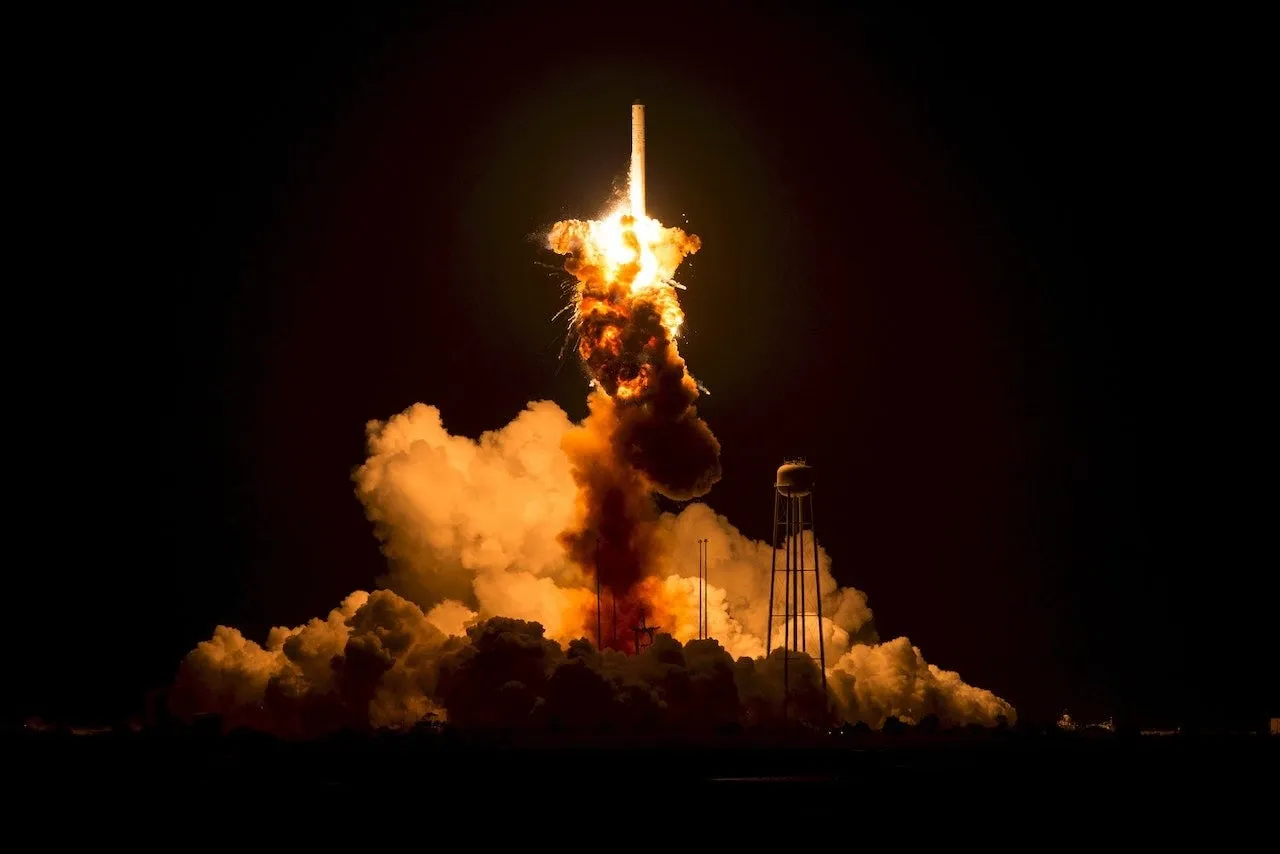 A rocket erupting in a fireball at night just after liftoff.