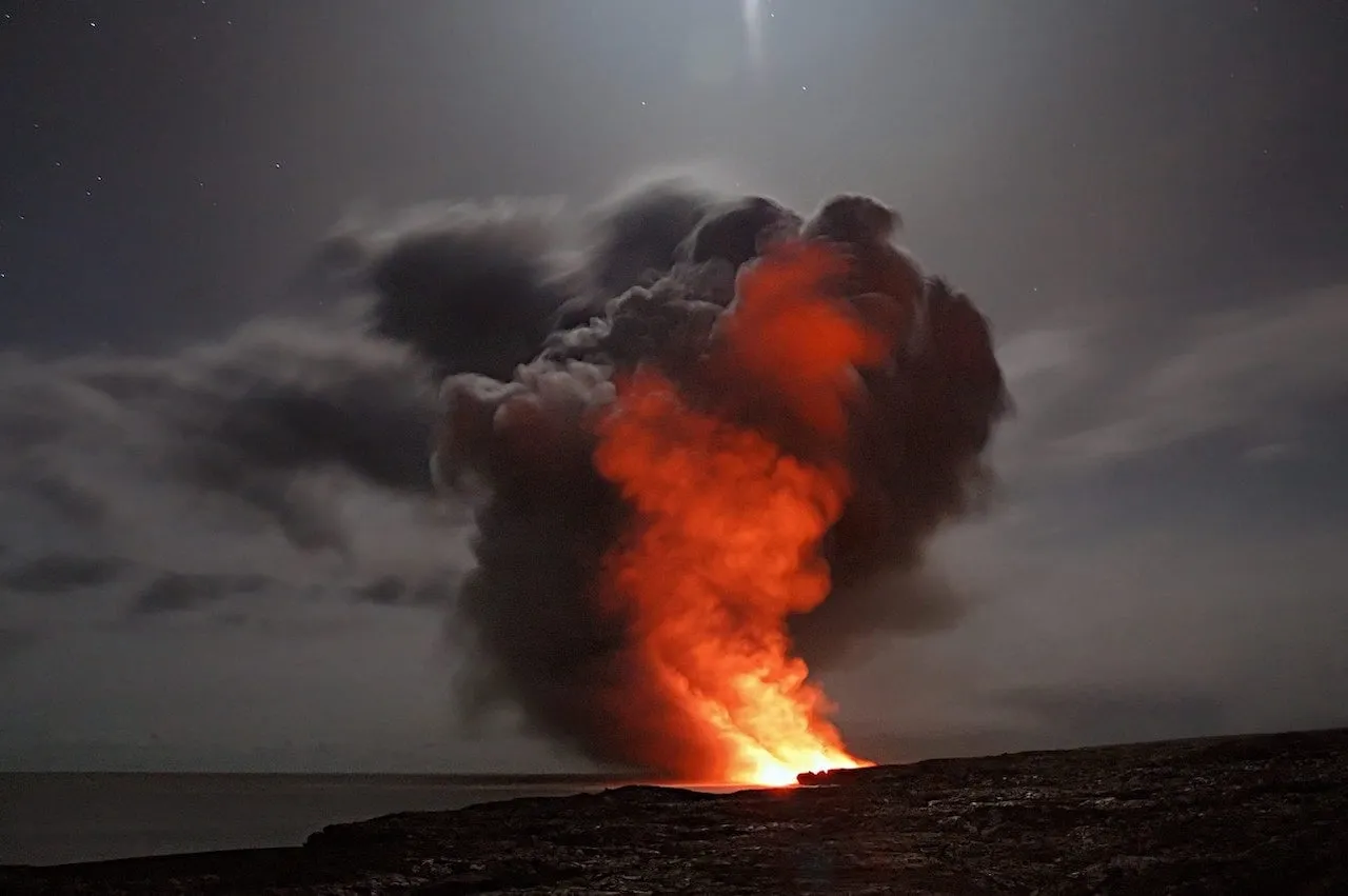A red-orange eruption of fire and smoke under a dark sky.