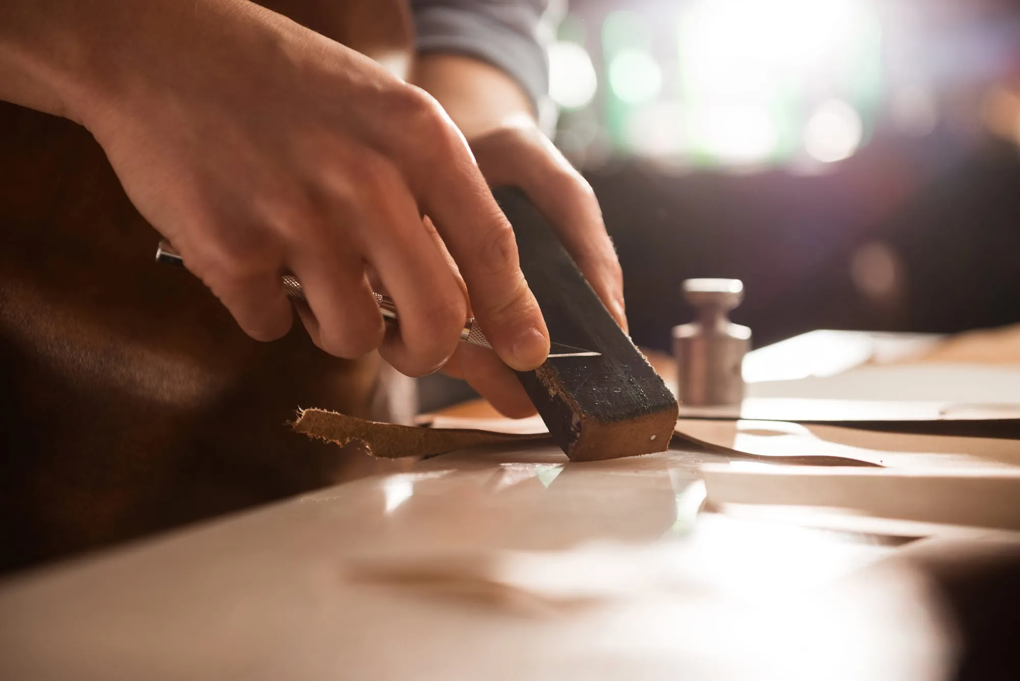 A craftsman’s hands sharpening a blade on a stone.