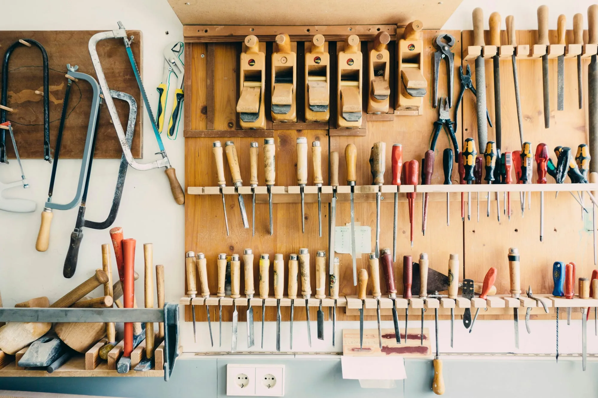 A wall of neatly arranged hand tools in a workshop.