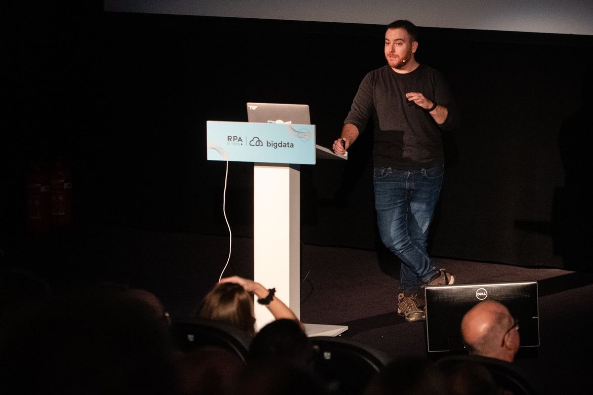 Yossi on the Big Data & RPA Europe stage beside the branded lectern, the audience in silhouette